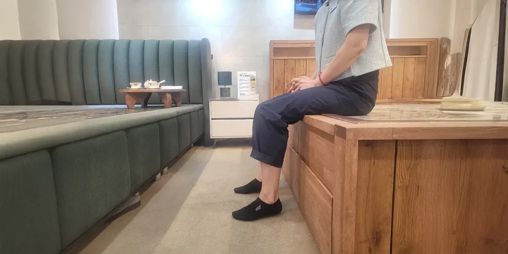 백화점 쇼룸에서 침대에 걸터앉아 높이를 확인하는 모습